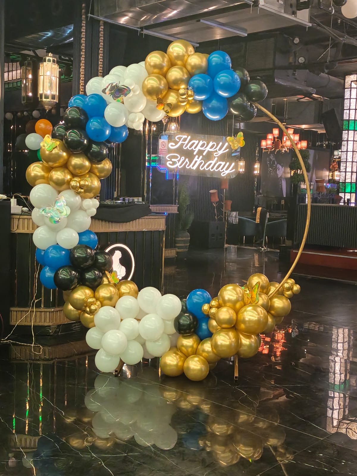 Blue gold and white balloon ring in a lounge with neon sign