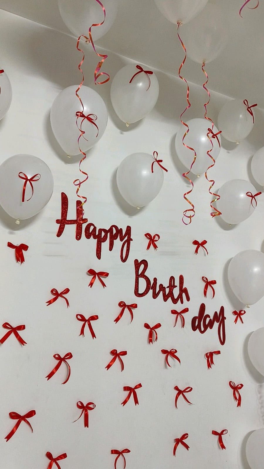 Room decoration with white balloons and red ribbon bows